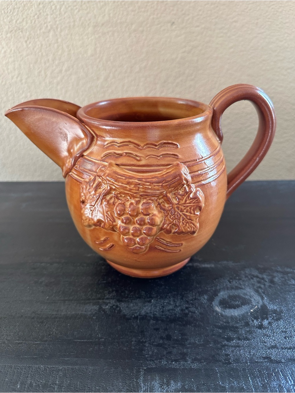 Vintage Italian honey-glazed ceramic pitcher with embossed grapes and vines.